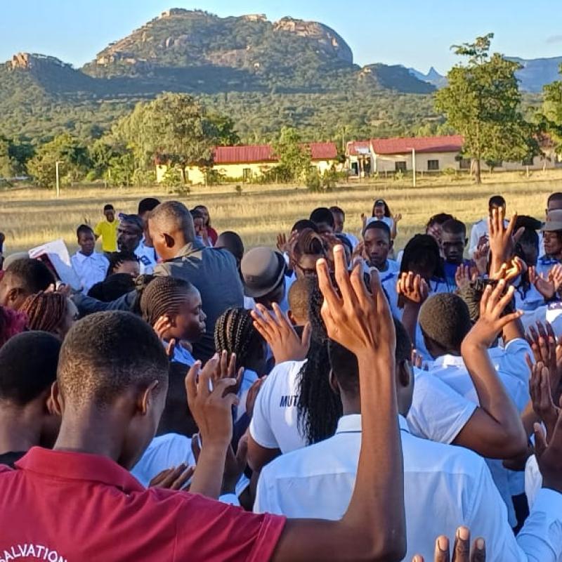 A crowd of people raise their hands in prayer
