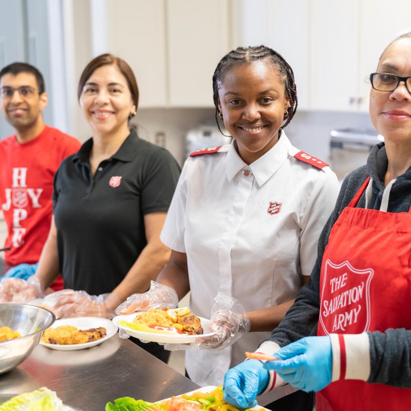 A team of four prepare plates of food
