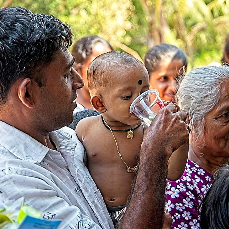 A young child drinks from a Salvation Army cup