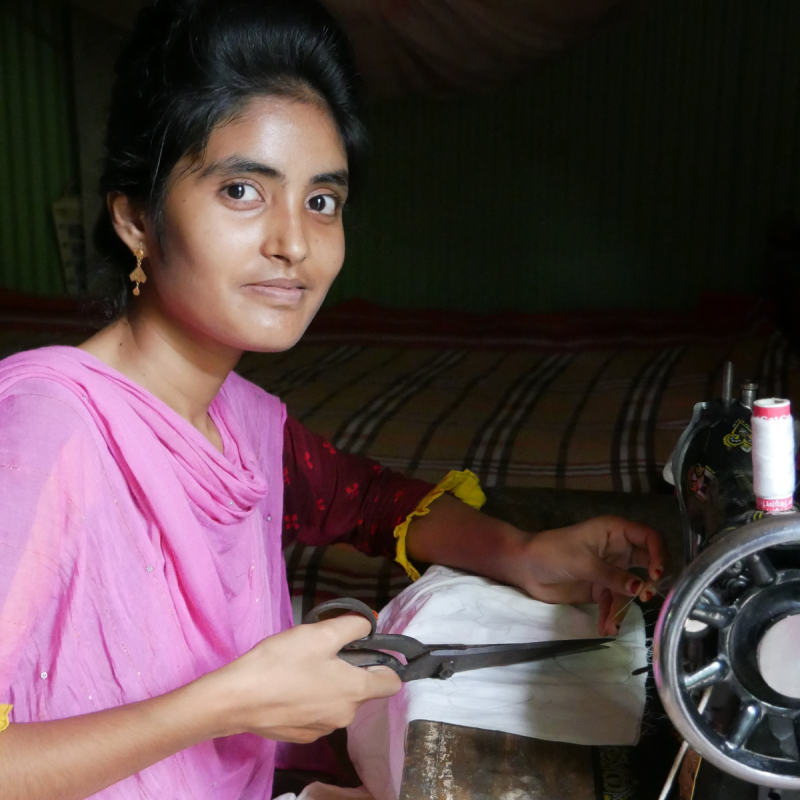 A woman sits at a sewing maching