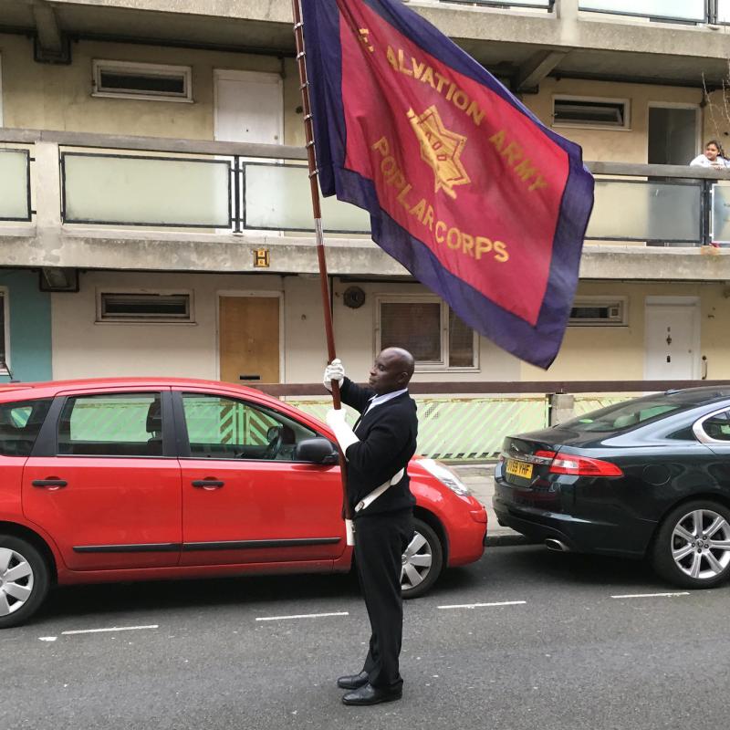 A Salvation Army soldier holds a corps flag aloft