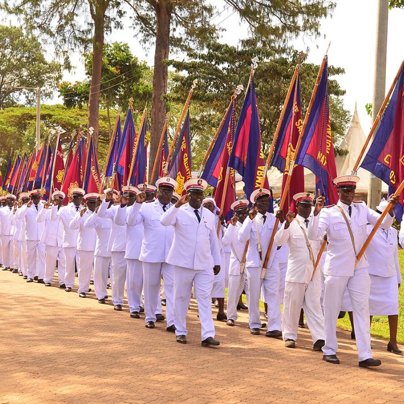 Salvationists in white uniforms march down the road