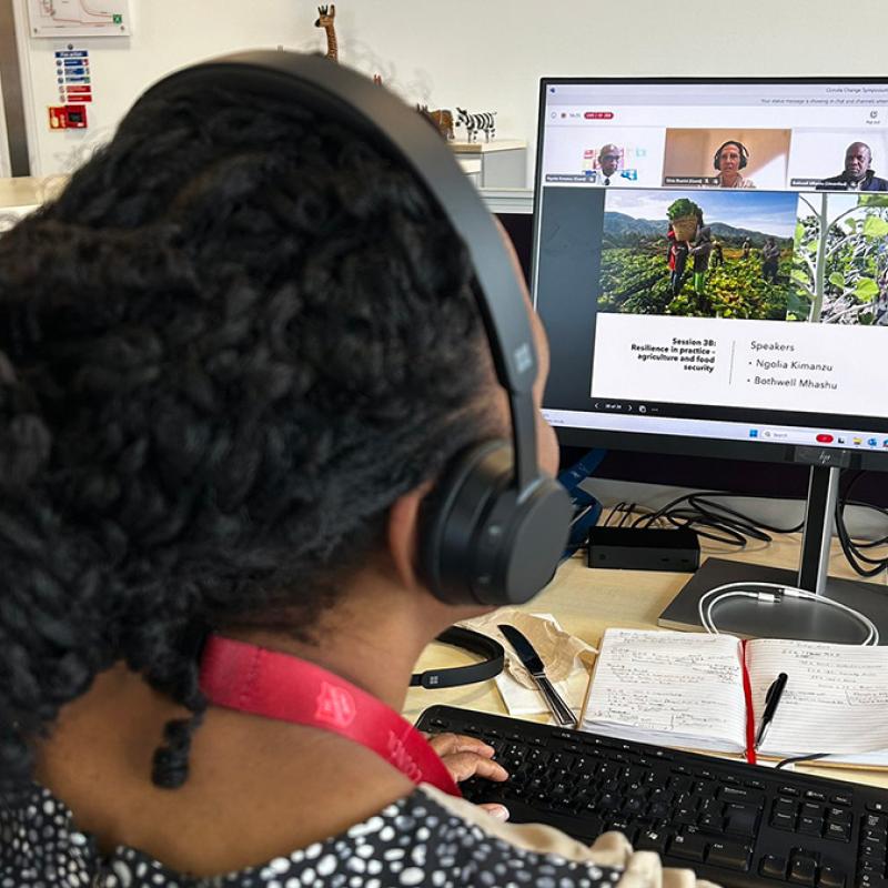 A woman joins the online symposium at her computer