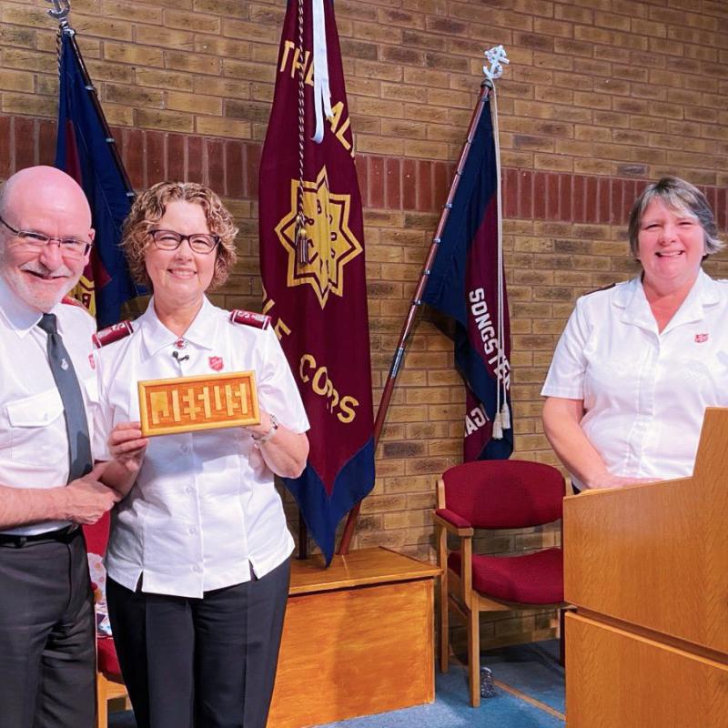 General Lyndon and Commissioner Bronwyn, pictured with corps officer Captain Jacqueline Coates, are gifted a 'Jesus board' during their visit to Dunstable