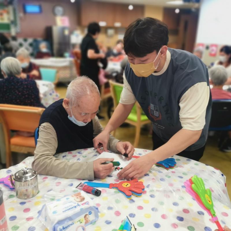 A carer assists a male resident in a care facility in Macau