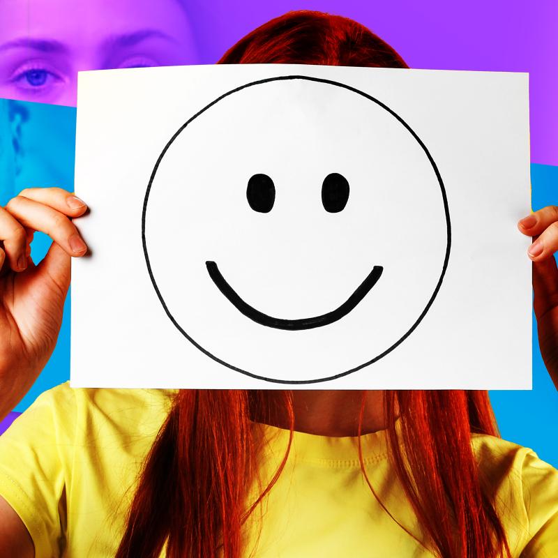 Young person holding up a smiley face